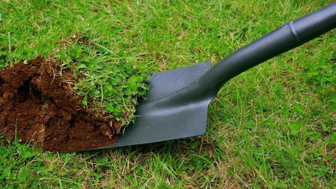 Shovel digs up a batch of grass and dirt.