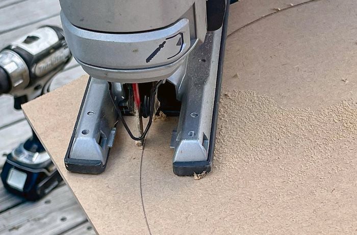  A person uses a jigsaw to cut an MDF panel to shape