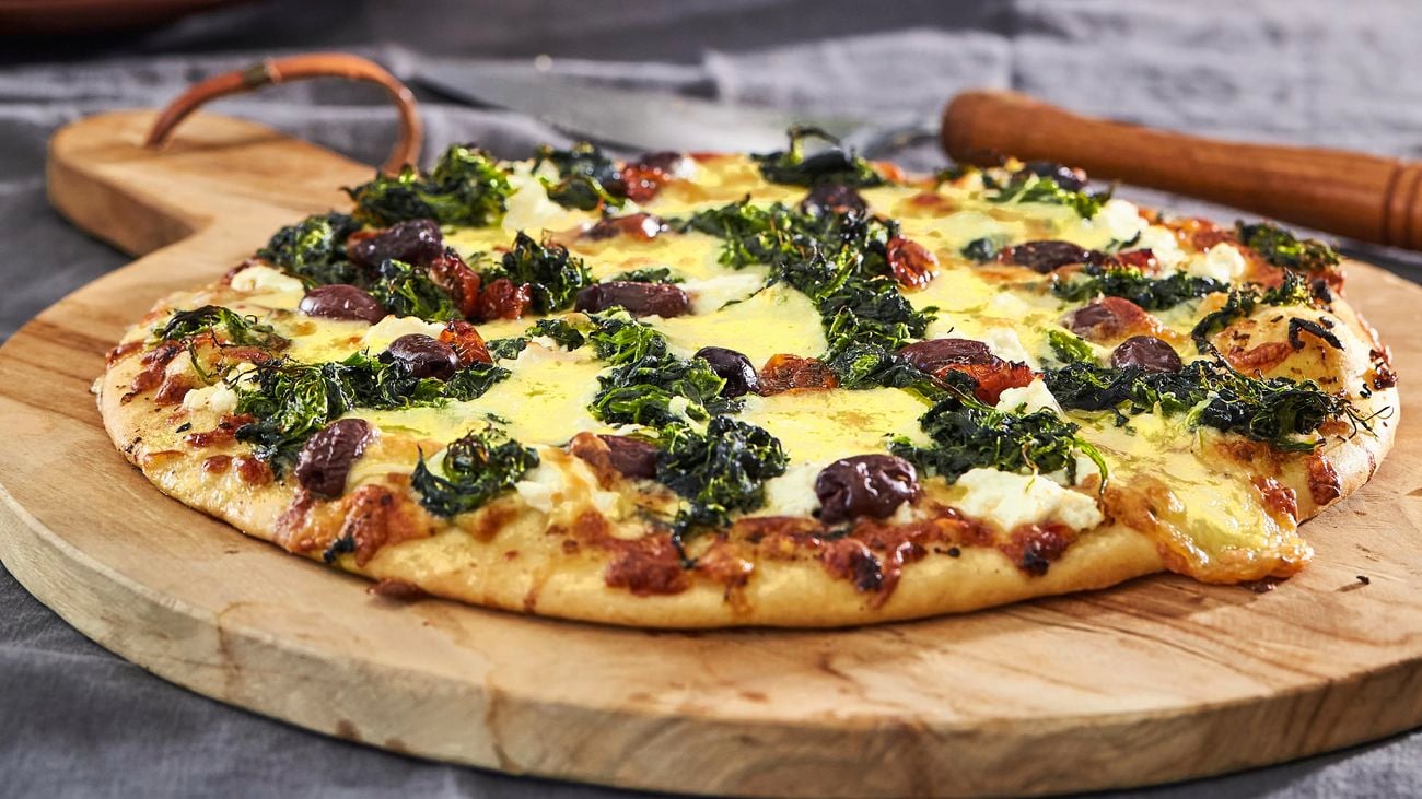 Close up of a cheese and spinach pizza on a dining table