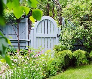 An arched picket fence style gate in a garden