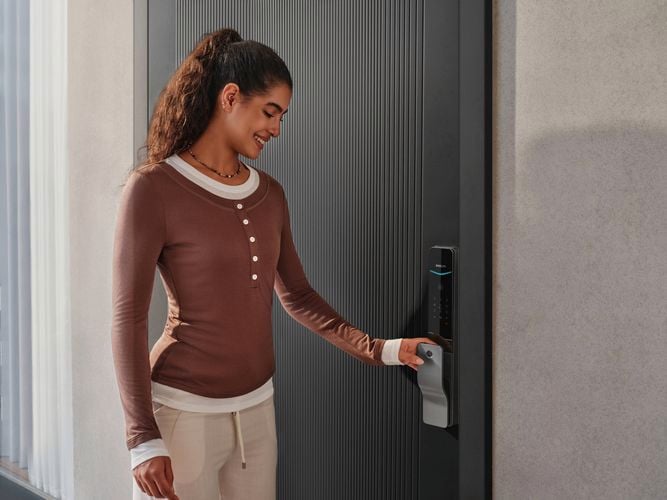 Person unlocking a front door using the fingerprint scanner on a Philips Smart Lock