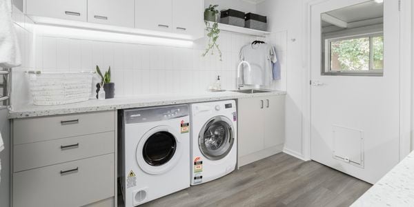 Laundry with cabinets, washer, dryer and timber flooring.