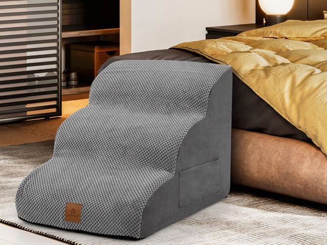 A grey pet ramp next to a bed in a bedroom.