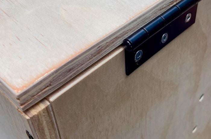 A wooden box with a hinge attached to the side of a panel