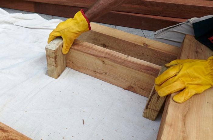 Framework for an outdoor day bed being measured for bolts with a square rule
