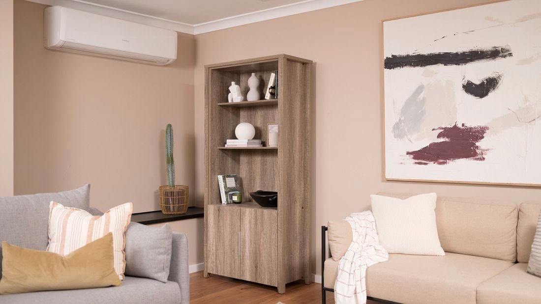 A room with two sofas, a painting, and a half-door storage cabinet by a heat pump.