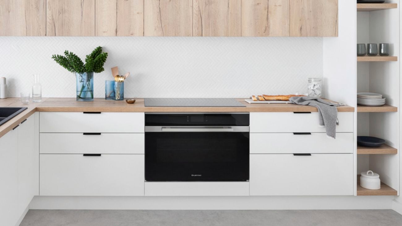 Kitchen with white and timber cabinets, a timber benchtop and floating shelves.