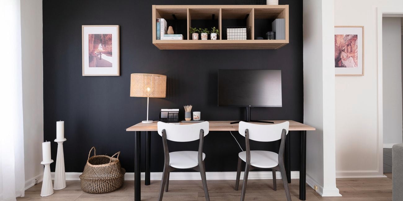 Black walls, timber desk and floating shelves.