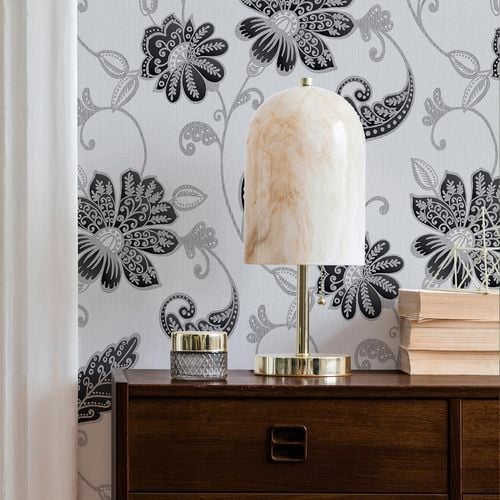 Table lamp and three books in front of a Boutique wallpaper wall.