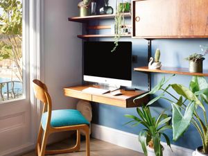 An office with a wooden desk, an Apple Mac computer, a wooden chair and blue walls.