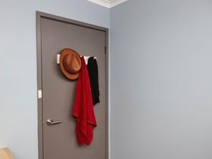 A hat and scarves hanging on a rack mounted on a bedroom door