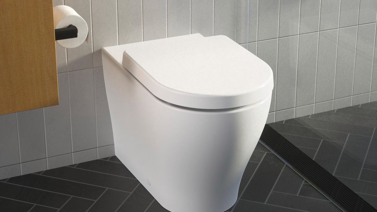 A Caroma wall faced toilet suite with the lid closed, installed in a black and white tiled modern bathroom.