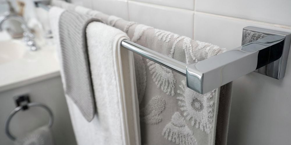 Chrome double towel rail with grey and white towels draped over
