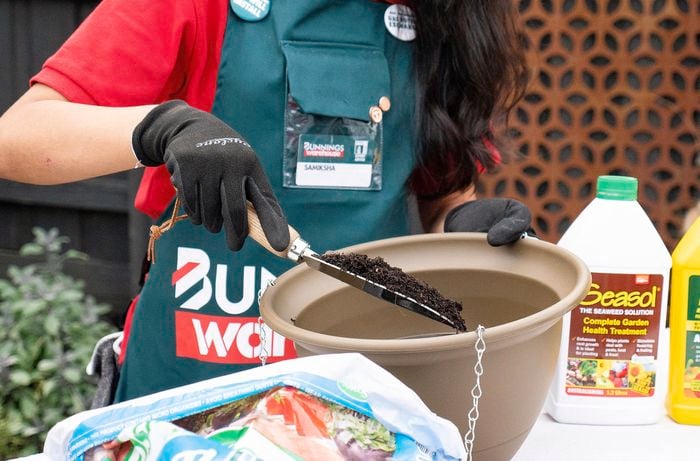 Bunnings Team Member using a spade to pour soil into a large pot