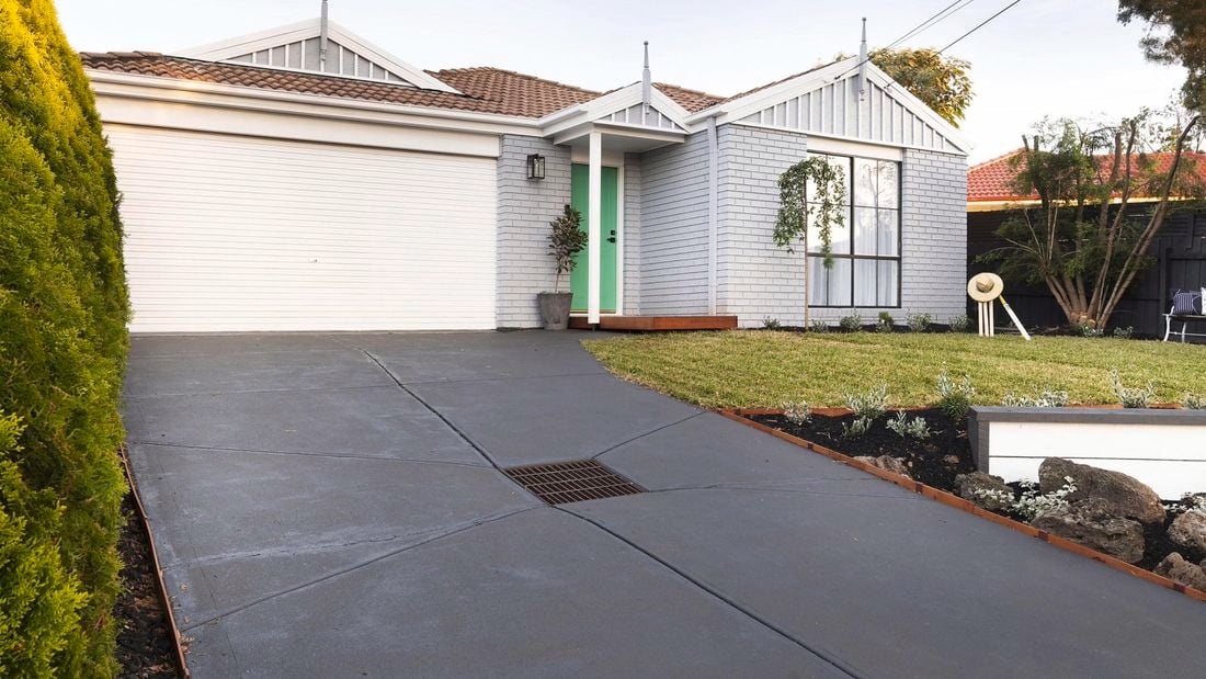 Exterior of brick house painted grey with a concrete driveway.