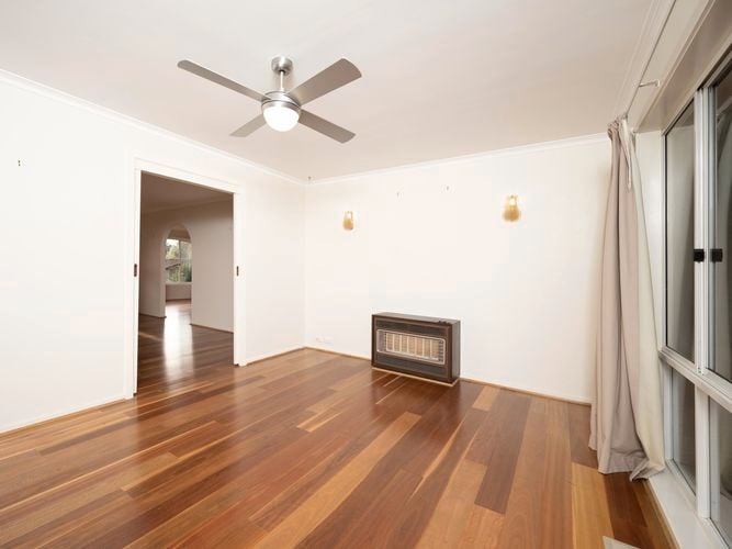 Empty room with wooden floorboards and a ceiling fan