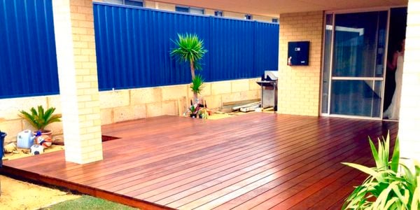A timber deck in an outdoor room next to grassed area