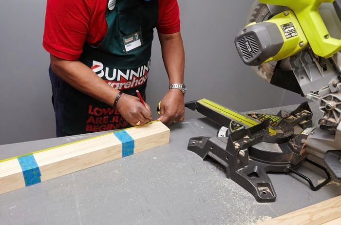 A person measuring lengths of pine timber taped together