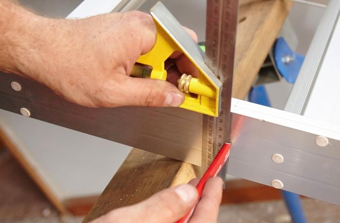 A person marking a line on the feet of an attic ladder