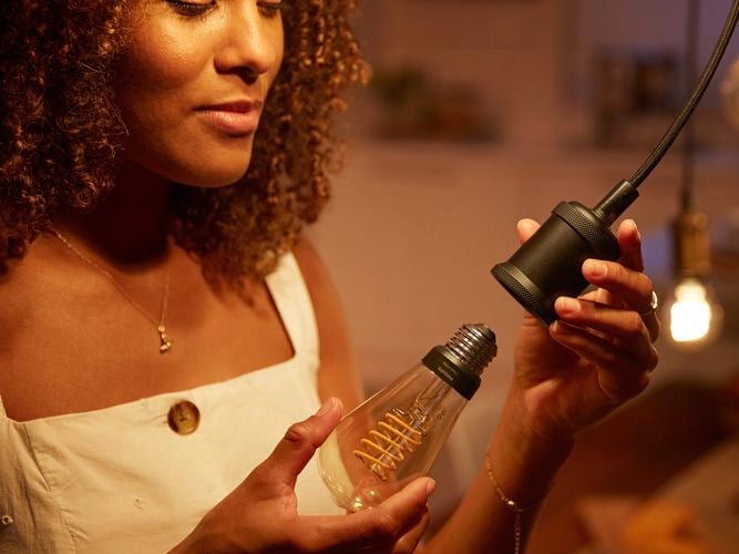 Philip hue brand - lady connecting a new light bulb into a light pendent