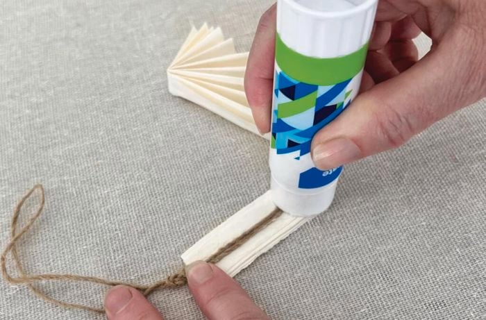 Hands glue twine to paper