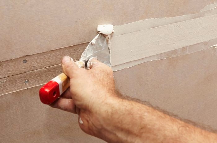 A gap between two sheets of villaboard being filled with plaster