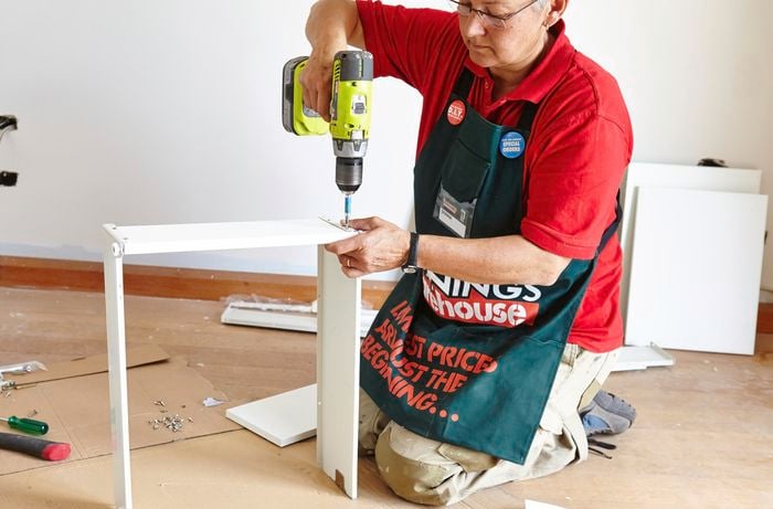 A person assembling a drawer using a cordless drill