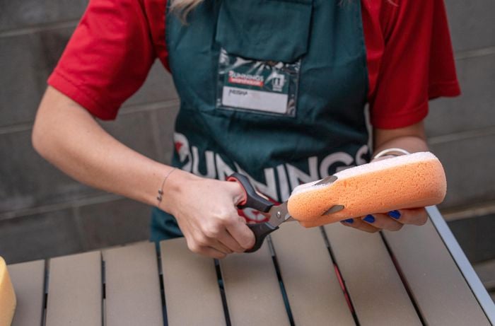 Woman cutting sponge into shape with scissors.
