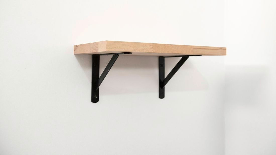 Timber wall shelf on wall with black brackets.