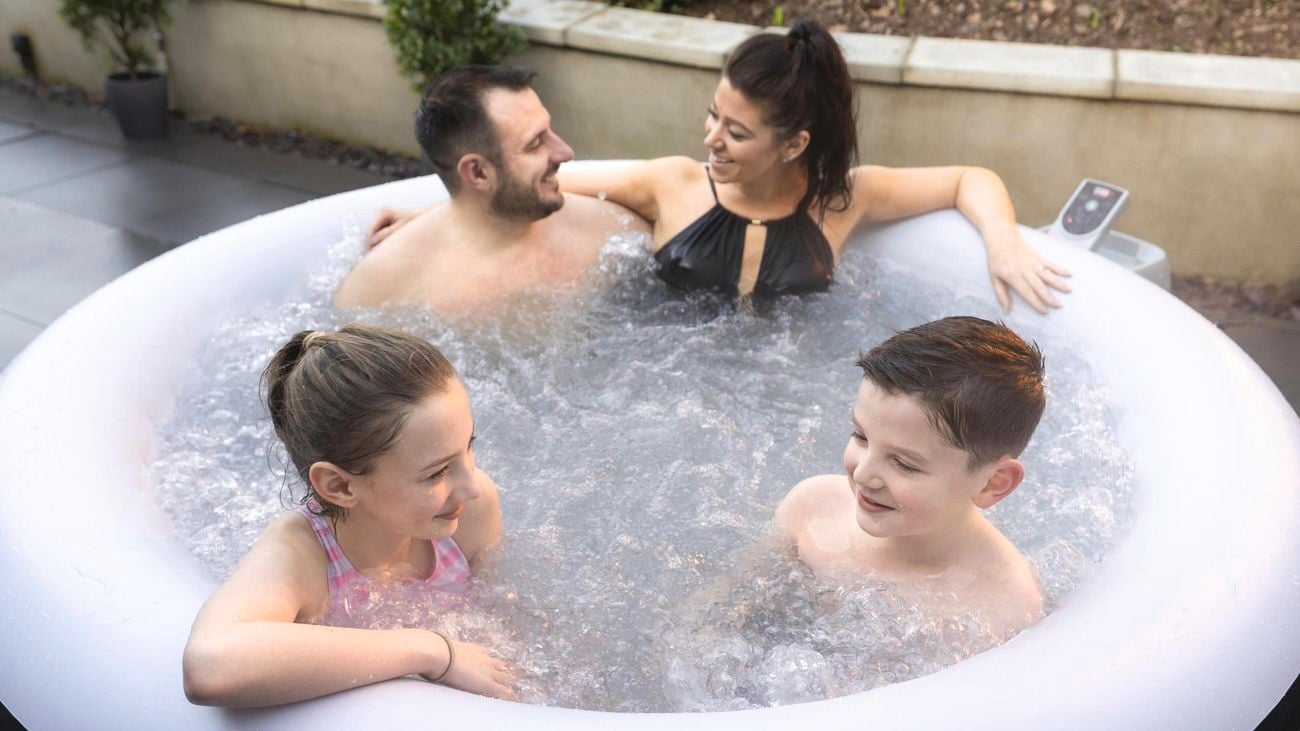 Family sit in a spa bath with in their yard with daughter and son and the front and mother and father at the back