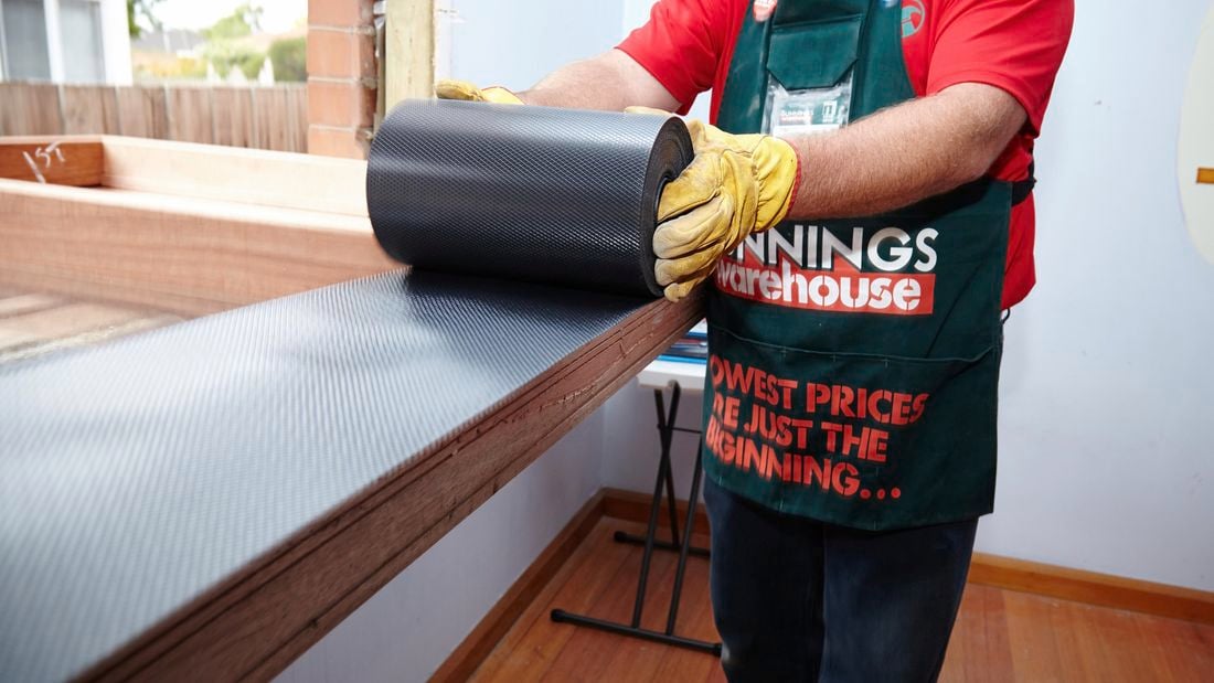 A Bunnings team member installing waterproof flashing onto the bottom of the casement window frame