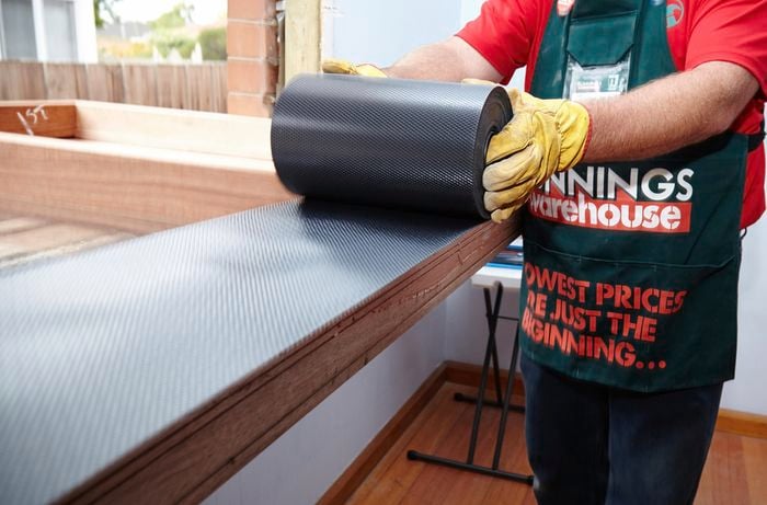 A Bunnings team member installing waterproof flashing onto the bottom of the casement window frame