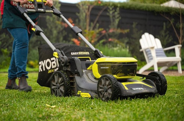 Bunnings team member mowing lawn using a ryobi mower