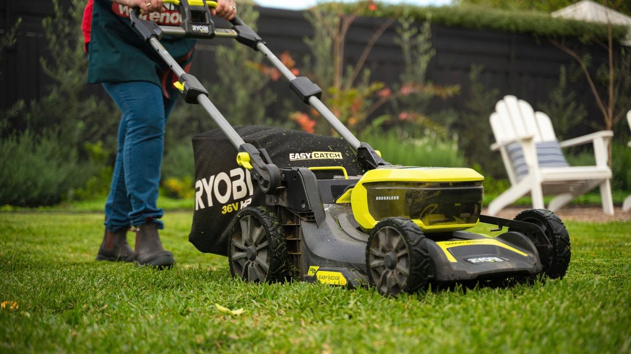 Bunnings team member mowing lawn using a ryobi mower