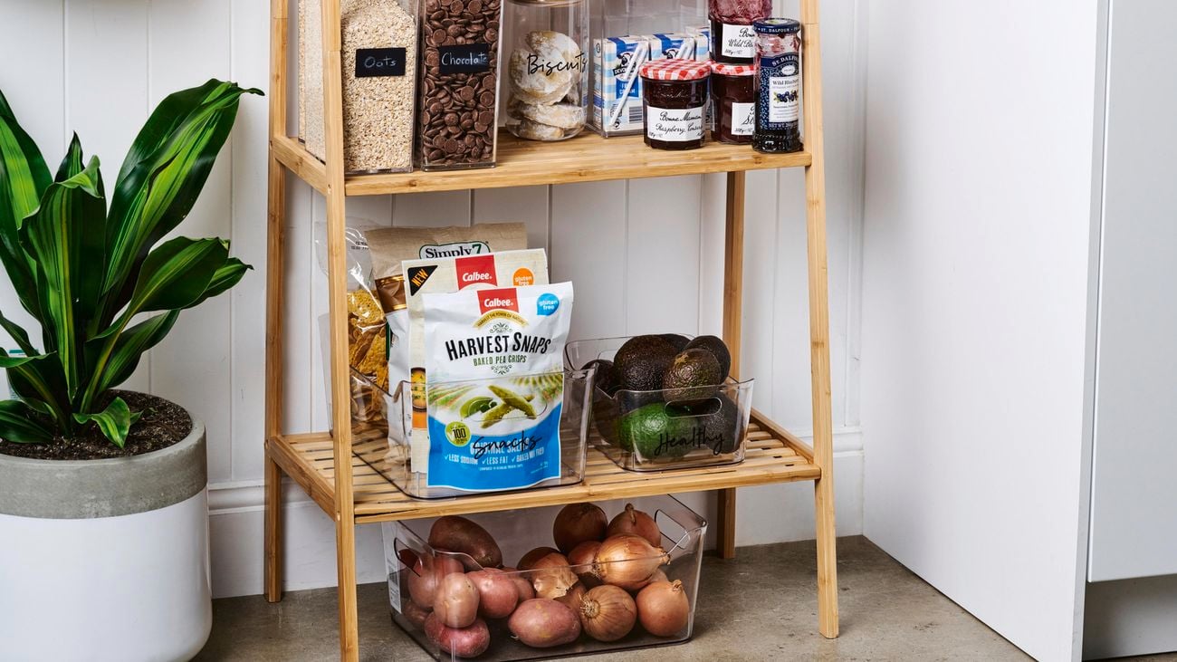 Organised timber kitchen rack, with stacked containers and jars of food and open shelves of vegetables.