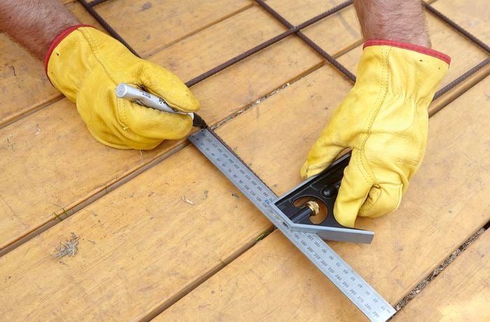 A square rule and a marker being used to mark a welding point on a wire mesh