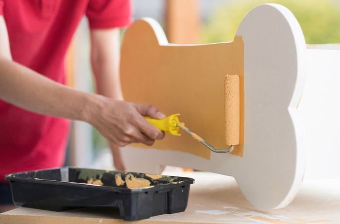 Painting the bone shaped dog toy box with a paint roller.