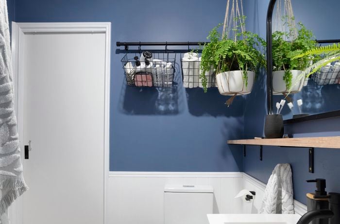 A completed bathroom storage basket rail in a blue themed bathroom with a hanging plant
