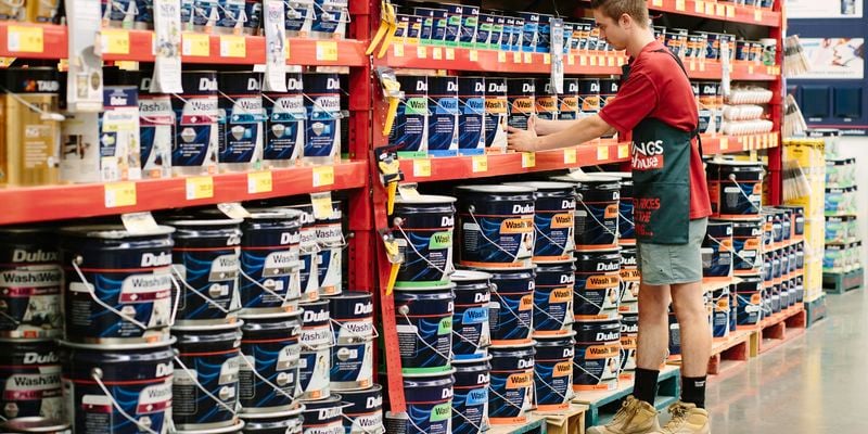 Bunnings team member re-filling a shelf with paint