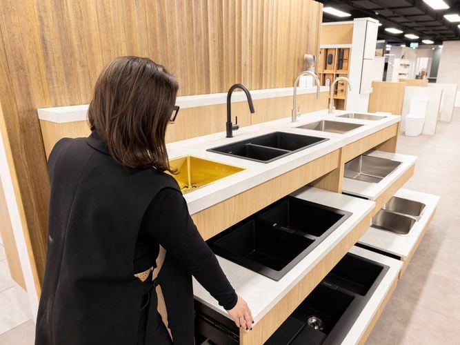 A lady with Kitchen sinks and taps in a display area.