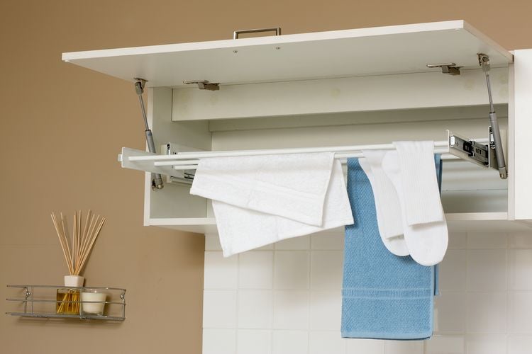 A foldaway drying rack with handtowels and socks, next to incense sticks on a wall mounted rack
