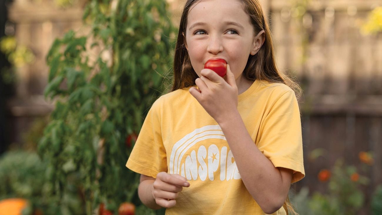 Girl eating a tomato.