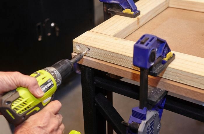 Person drilling wooden garden bench frame together.
