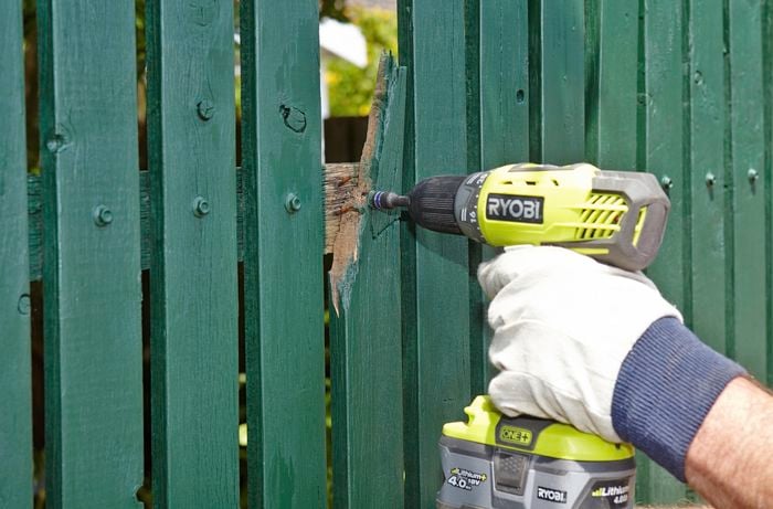 Person using impact driver to remove nails from picket fence.
