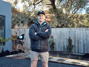 A landscape gardener with a coat on and his hands folded across his chest