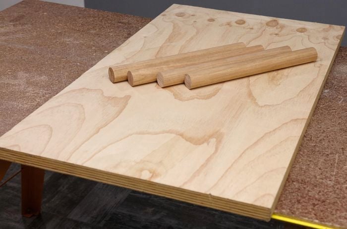 A sheet of thick plywood and four lengths of dowel