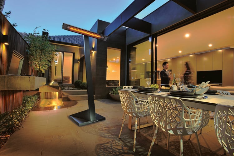 Outdoor dining area with water feature heated by freestanding heat lamp