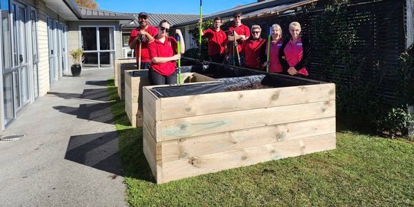 Lots of Bunnings Team Member's holding garden tools around Raised wooden garden beds.