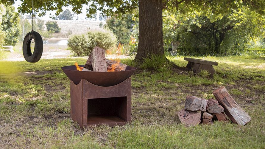 A lit brazier in a garden, with a tyre swing hanging in the background