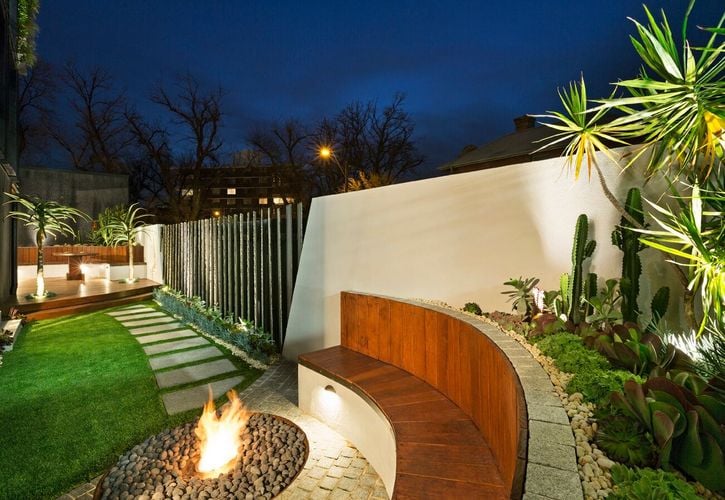 A curved seating area around a firepit as part of an outdoor setting at night